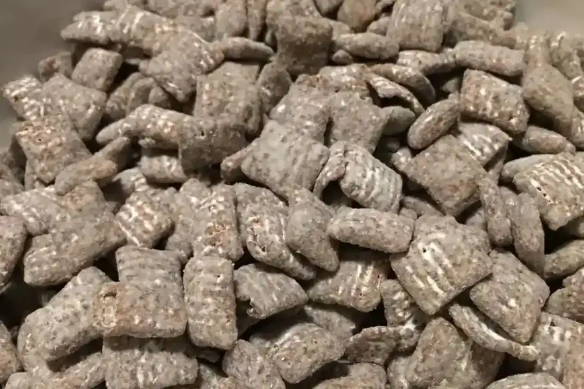 A bowl of classic Muddy Buddies dusted with powdered sugar.